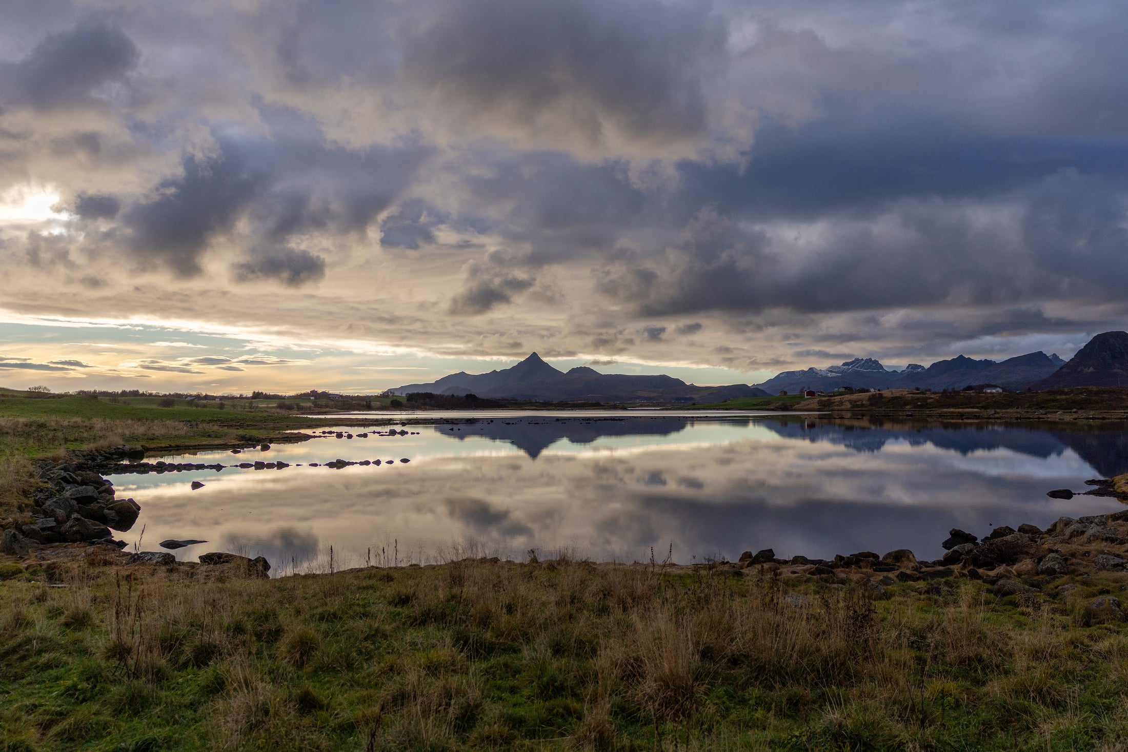 Berge in der Distanz spiegeln sich im Wasser bei stimmungsvoller Abendbeleuchtung